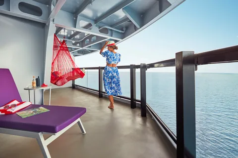 A traveler on a cruise ship balcony looking out across open ocean.